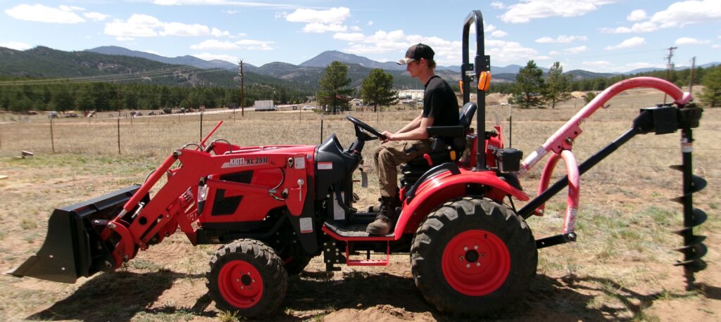 man operating a 24HP Kioti Compact Tractor with Rear auger