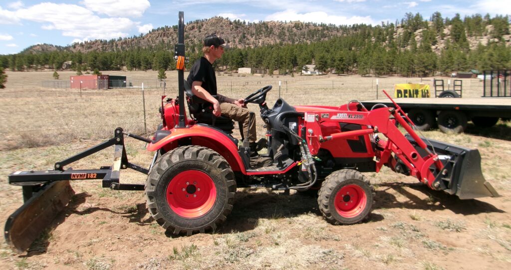 man sitting on 24HP Kioti Compact Tractor with Rear Blade