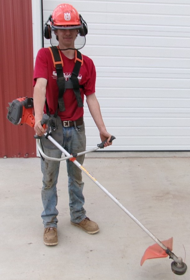 Man with helmet and outdoor gear using a Husqvarna Weed Trimmer at Hitchin Post Trailer and Tractor Sales Rentals