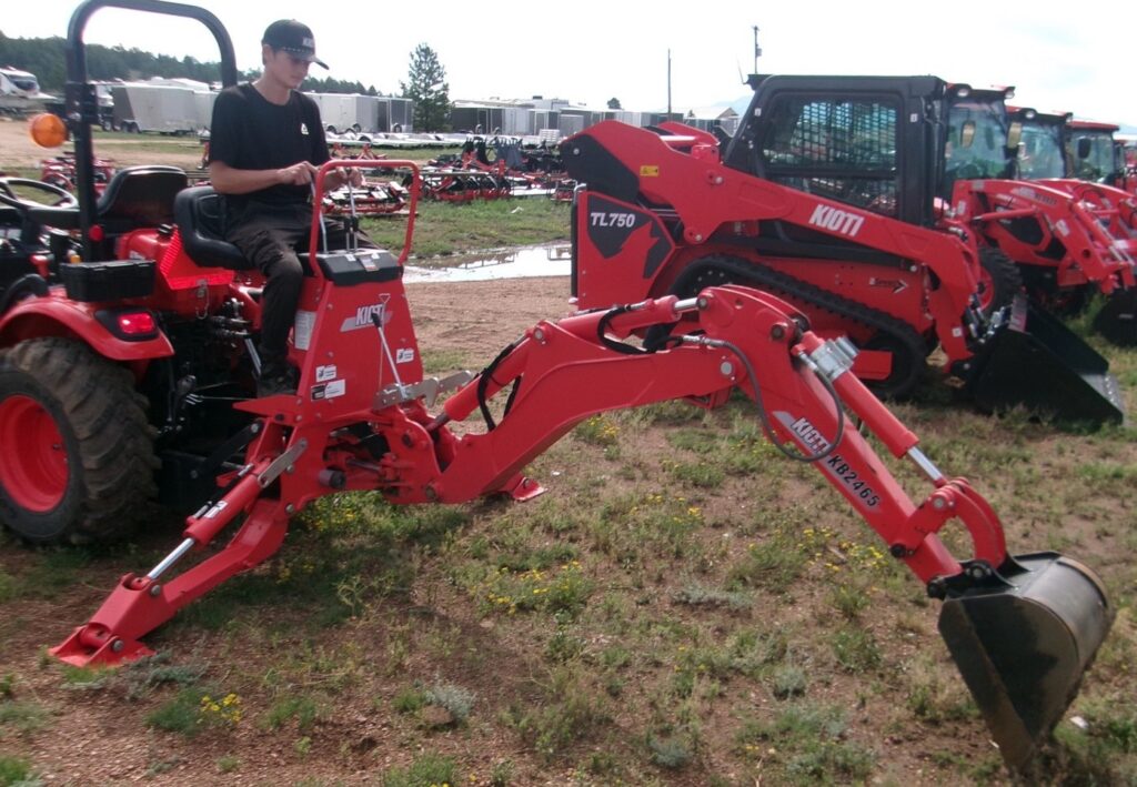 man sitting on 24HP KIOTI Compact Tractor and Rear Backhoe