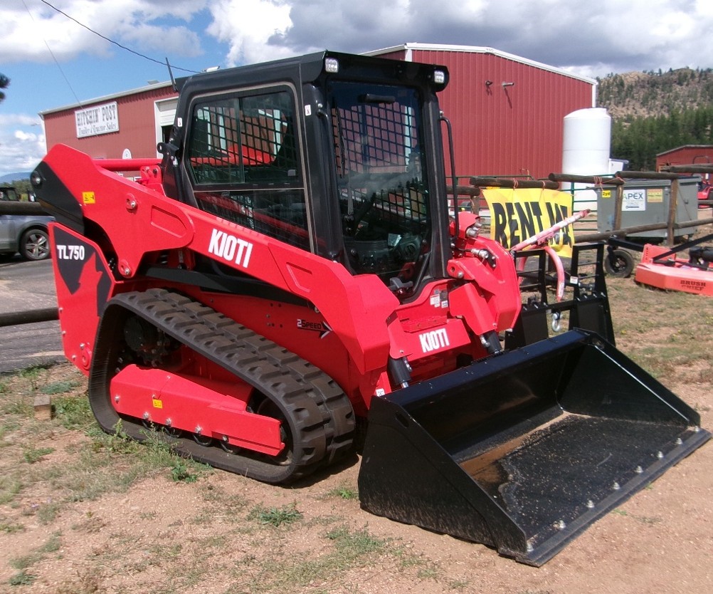KIOTI TL750 Trac Loader with Bucket sitting outside on dirt lot with building in the background.